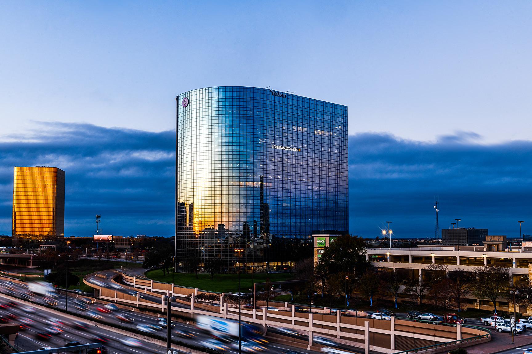 High rise building in Dallas stands beside busy freeway.