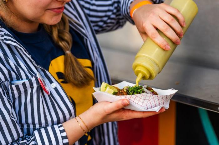 Closeup of student squeezing tube of sauce on to plate of food